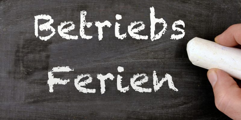 A,Person,Writing,The,German,Words,Betriebsferien,On,A,Chalkboard,